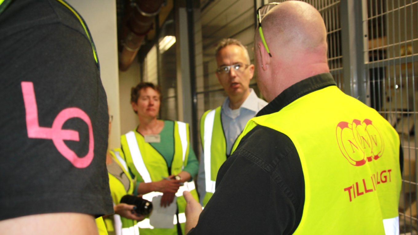 Personer i gule refleksvester på arbeidsplass. Foto.